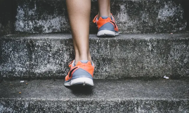 Pomarańczowe buty sportowe na siłownię, idealne na trening, wspinają się po betonowych schodach.