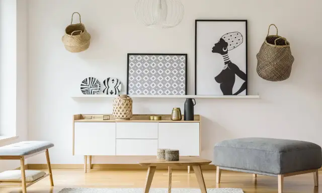 Un mueble blanco resalta sobre una pared clara, complementado con cestas de mimbre y arte africano. El color de pared para muebles blancos es neutro y elegante.