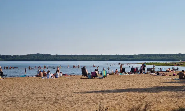 Folk njuter av solen och badar vid en strand, en perfekt plats för camping i Luleå.