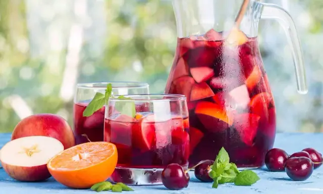 Une carafe et des verres de sangria rouge remplis de fruits frais, parfaits pour une recette de sangria rouge estivale.