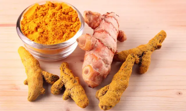 Racines de curcuma fraîches et en poudre, symboles des nombreux curcuma bienfait pour la santé.