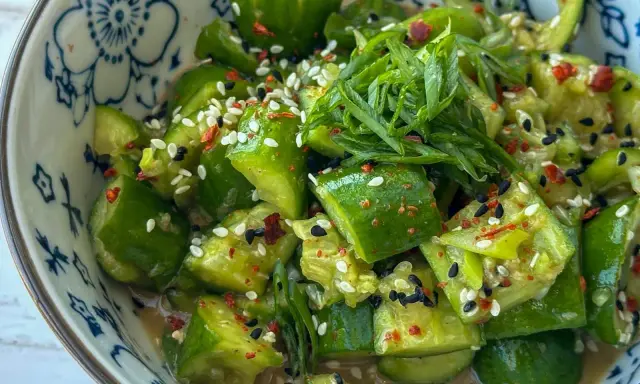 Erfrischender asiatischer Gurkensalat mit Sesam, Chili und Frühlingszwiebeln in einer blumengemusterten Schüssel.