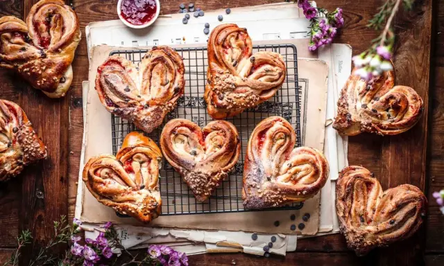 Herzförmige Hefeteilchen mit Marmelade und Nüssen, liebevoll arrangiert auf alten Notenblättern.