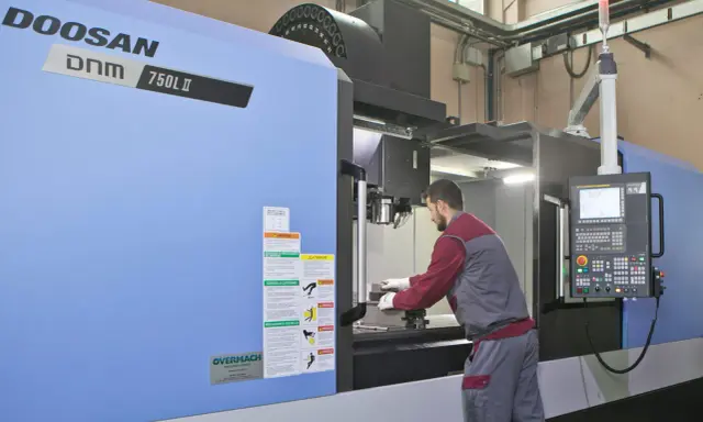 Operaio lavora su centro di lavoro CNC, strumento essenziale per il software progettazione e la produzione di precisione.