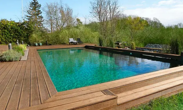 En vacker klorfri pool med trädäck och grönskande omgivning. Perfekt för avkoppling i naturen.