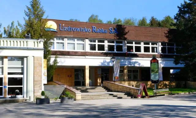 Sanatorium Jagiellonka w Rabce-Zdroju, budynek z napisem "Uzdrowisko Rabka S.A." i dużą butelką solanki.