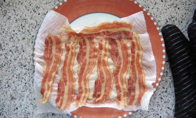 Fertig zubereitetes Bacon auf Küchenpapier auf einem Teller. Schnell und einfach in der Mikrowelle gemacht.