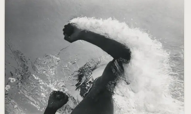 Underwater shot of a swimmer's arms and torso, creating a dramatic splash. The image captures the power and motion of a flip schulke.