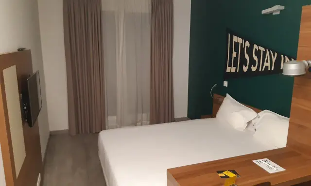 Habitación moderna en The Student Hotel Paris. Cama blanca, escritorio de madera y decoración "Let's Stay In".