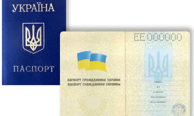 Ukraiński paszport, otwarty na stronie z danymi i flagą.
