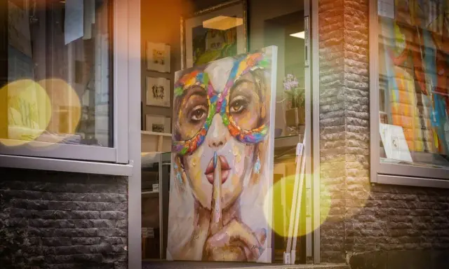 A vibrant painting of a woman in a colorful mask hints why rich people buy art: for beauty, status, and a touch of mystery.