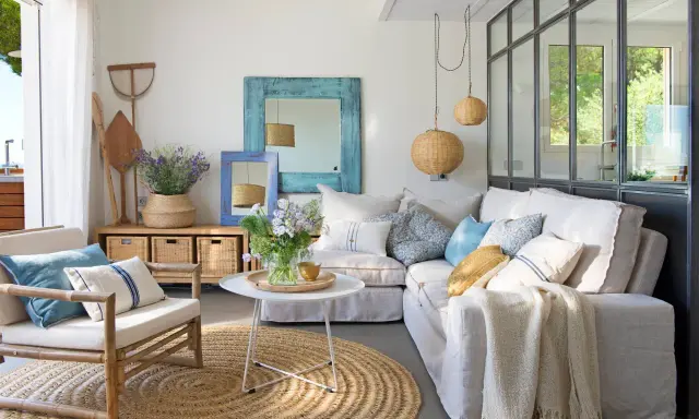 Ideas para decorar casa playa poco presupuesto: sofá blanco, alfombra de yute, cestas de mimbre y detalles marineros.
