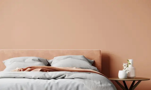 Lit de chambre douillet avec mur et tête de lit couleur pêche. Quelle couleur chambre pour une ambiance chaleureuse et apaisante.