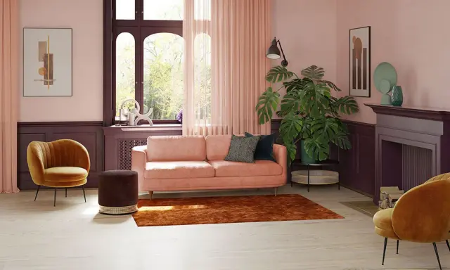 Przytulny salon z sofą w kolorze pudrowy róż, aksamitnym fotelem i dywanem w odcieniu miedzi.