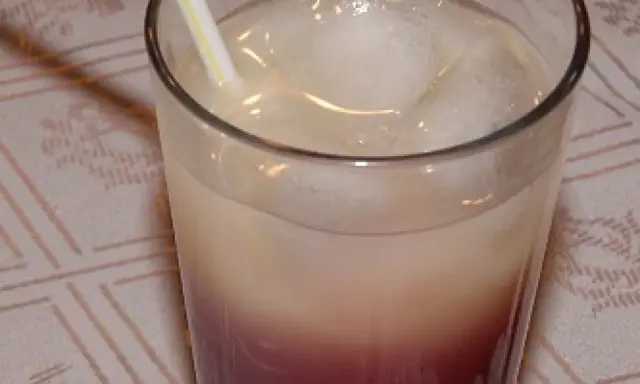 Szklanka z drinkiem z lodem i słomką, z widocznym podziałem na warstwy koloru.