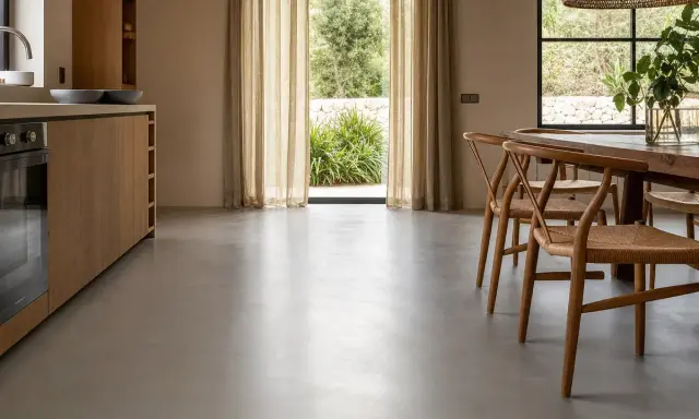 Cocina moderna con muebles de madera y un elegante suelo microcemento que refleja la luz natural.