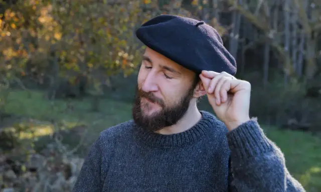 Hombre con barba ajustando su boina de lana, ideal para aprender como hacer una boina de lana.