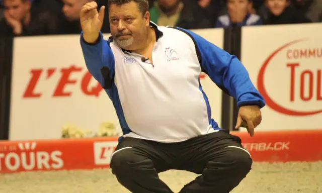 Un joueur de pétanque français connu, en pleine action, lance sa boule.