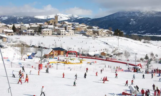 Un pueblo nevado en el Pirineo francés con niños esquiando y divirtiéndose en la nieve.