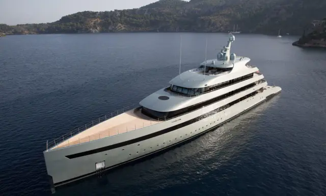 Un yacht de luxe gris clair navigue dans une baie. Le choix couleur coque bateau est élégant, contrastant avec le bleu profond de l'eau.