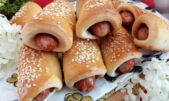 Złociste, pieczone mini hot dogi posypane sezamem, gotowe do podania. Idealne na przekąskę!