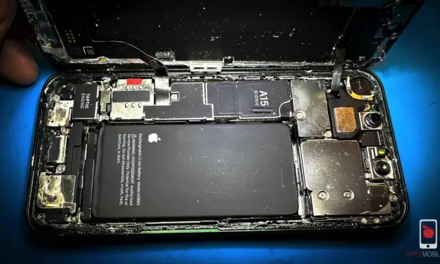Rozkręcony iPhone z widoczną baterią i procesorem A15 Bionic. Wygląda na to, że ten zalany iPhone wymaga pilnej naprawy.
