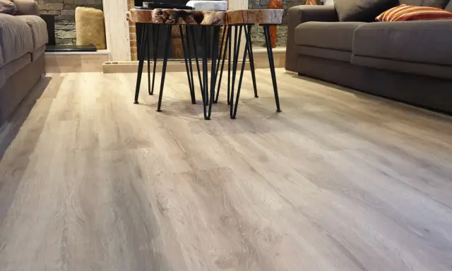 El suelo laminado o parquet de madera clara se extiende por la sala, reflejando la luz.