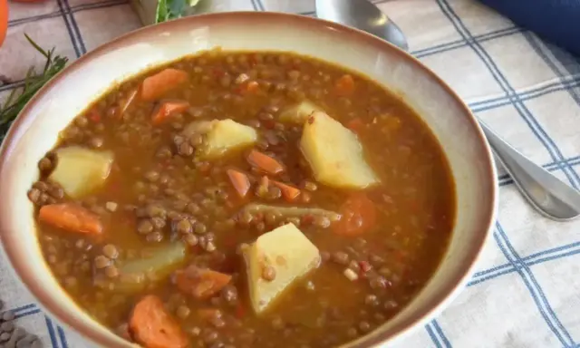 Un plato humeante de lentejas estofadas al estilo Arguiñano, con patatas y zanahorias, listo para disfrutar.
