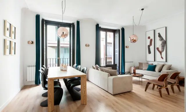 Amplio salón comedor rectangular de 25 metros con sofás, mesa de madera y sillas modernas.