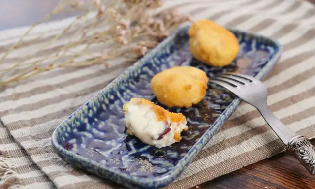 Deliciosa croqueta de jamón, cremosa por dentro y dorada por fuera, servida en un plato azul.