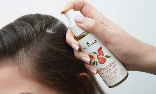 Dłoń aplikuje spray na skórę głowy, by uzyskać proste włosy.