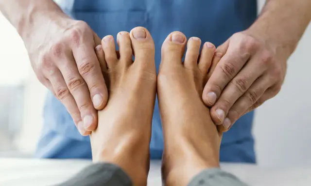 Fizjoterapeuta bada stopy pacjenta, aby zdiagnozować drętwienie palców u nóg.