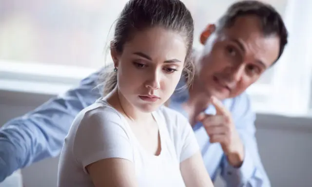 Mujer triste, hombre la señala. Una escena que evoca el trauma bonding español, donde el dolor crea un vínculo perverso.