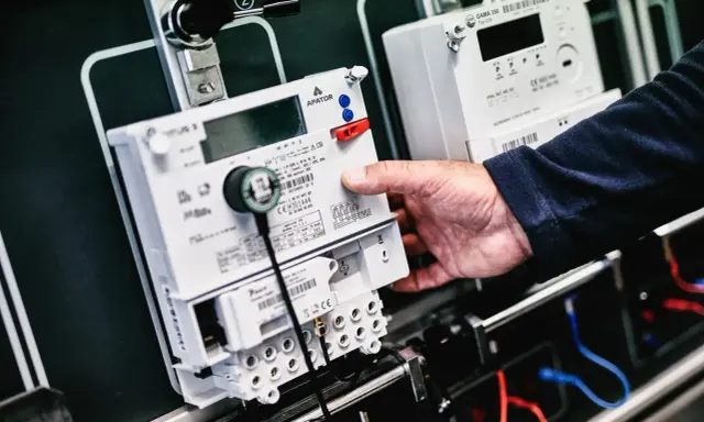 Dłoń manipuluje przy liczniku zdalnego odczytu PGE. Nowoczesne urządzenia do monitorowania zużycia energii.