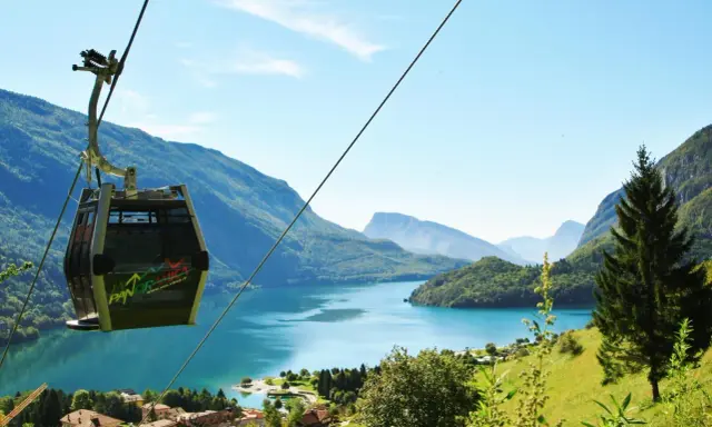 Cabina panoramica sul lago di Molveno, con montagne sullo sfondo. Si intravede una cascata tra gli alberi.