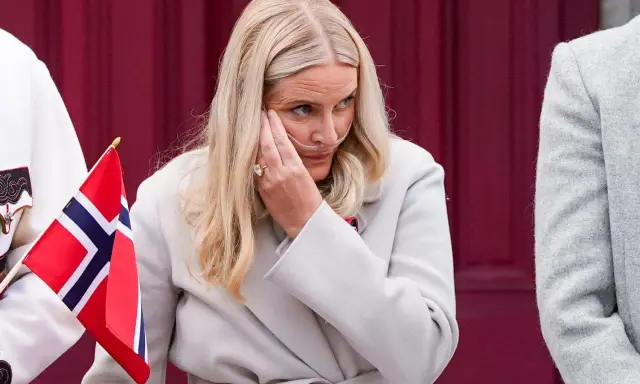 Kronprinsessan Mette-Marit med syrgasgrimma, en påminnelse om hennes sjukdom, håller en norsk flagga.