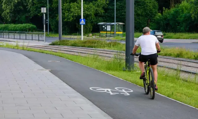 Mężczyzna na rowerze na ścieżce, obok torów tramwajowych. Uważaj, bo mandat za prowadzenie roweru pod wpływem alkoholu jest wysoki.