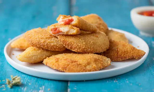 Sofficini fatti in casa dorati e croccanti, ripieni di pomodoro e formaggio filante, pronti per essere gustati.