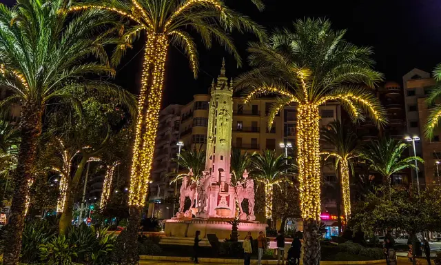 Nocna iluminacja palm i fontanny z rzeźbami. Wspaniała atmosfera, jakby trwały święta w Hiszpanii.