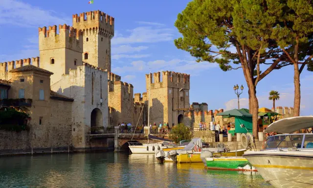 Castello Scaligero sul lago, ideale per vacanze in Lombardia. Barche ormeggiate in un porto pittoresco.