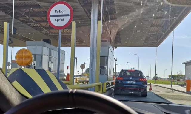 Kolejka samochodów do punktów poboru opłat. Znak informuje o poborze opłat.