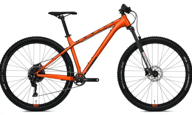 Pomarańczowy rower górski z amortyzowanym widelcem. Czy to hardtail czy full? Ten model to klasyczny hardtail, gotowy na wyzwania.