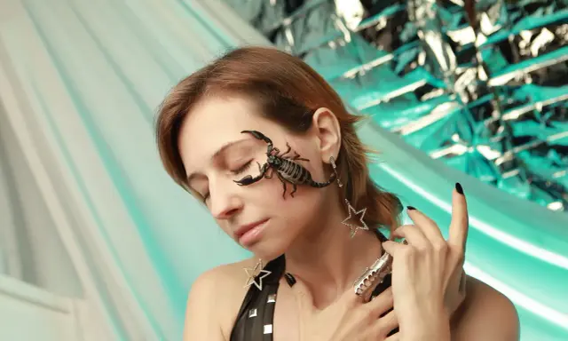Scorpione sul viso di una donna, un esempio estremo di desensibilizzazione sistematica. Gioielli a forma di stella e un anello elaborato completano il look.