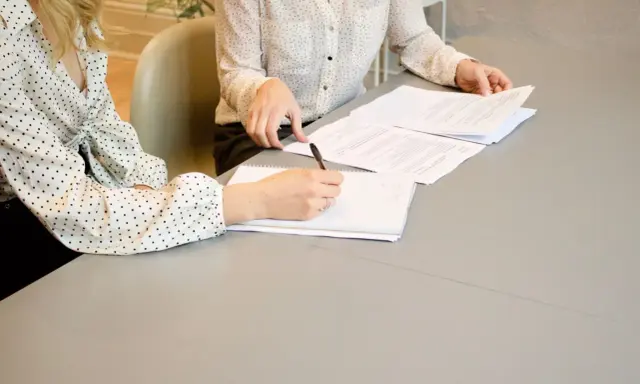 Nauczycielka z uśmiechem pisze na tablicy, przygotowując materiały na kolejne dni robocze.