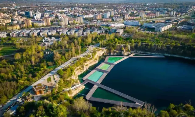 Widok na zakrzówek kapielisko z basenami w kamieniołomie, otoczone zielenią i zabudową miejską.