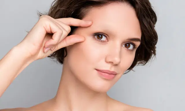 Une femme examine son visage, préoccupée par une possible alopécie sourcil.