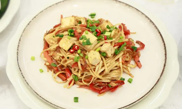 Pyszny makaron z tofu, papryką i szczypiorkiem, posypany chili. Idealne danie dla wegan.