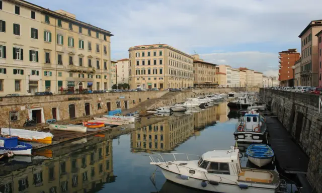 Canali e palazzi storici a Livorno, perfetti per gite di un giorno. Barche ormeggiate riflettono l'architettura.