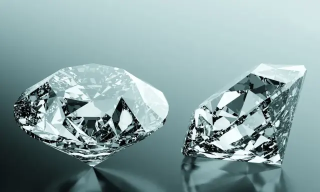 Due diamanti scintillanti, uno rotondo e uno a goccia, riflettono la luce. Uno dei due, un diamante brown, brilla con sfaccettature perfette.