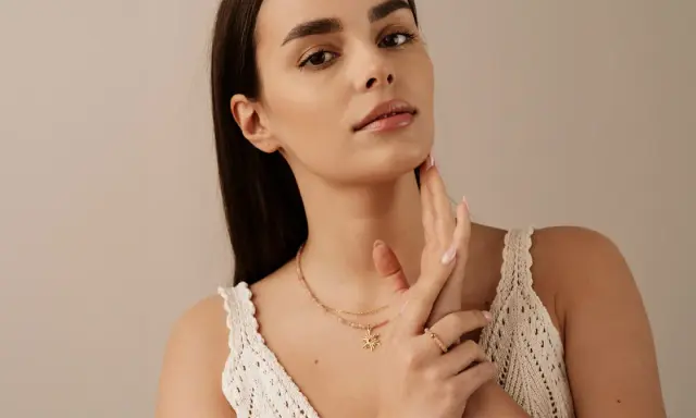 Delikatny choker z zawieszką w kształcie słońca, noszony przez kobietę z subtelnym makijażem.